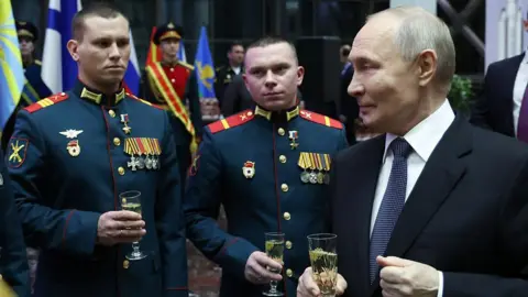 Alexander KAZAKOV/POOL/AFP A man with a glass stands on the right of two men in uniform