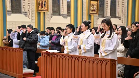 Getty Images Worshippers attend a Christmas Eve mass at the Church of the Saviour in Beijing, China on 24 December.