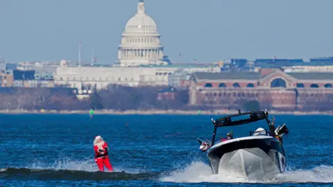 Getty Images A skiing Santa delights crowds during an annual Waterskiing Santa event in Alexandria, Virginia in the US on 24 December 2025.