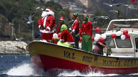Getty Images Fishermen dressed as Santa and the Grinch on a boat in Valparaiso Bay, Chile on 24 December.