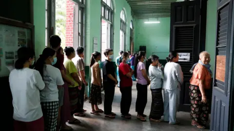 EPA/Shutterstock A queue if people, many wearing face masks, as they wait to cast their ballots.
