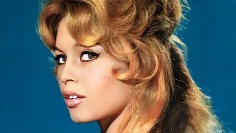 Herbert Dorfman/Corbis via Getty Images Brigitte Bardot looks at the camera, mouth slightly open, her blonde hair curled around her face, wearing black winged eyeliner.