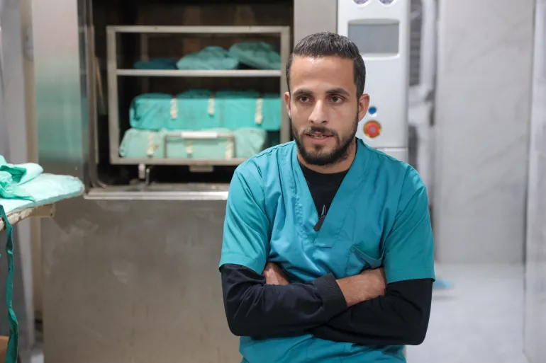 Doctor in scrubs sitting with arms crossed