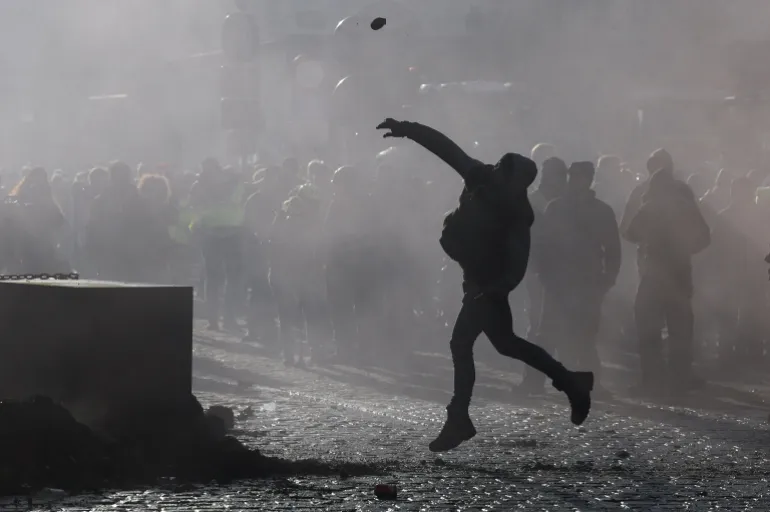 A protester throws an object, as farmers protest against the EU-Mercosur free-trade deal between the European Union and the South American countries of Mercosur, on the day of a European Union leaders' summit, in Brussels, Belgium, December 18, 2025. REUTERS/Yves Herman