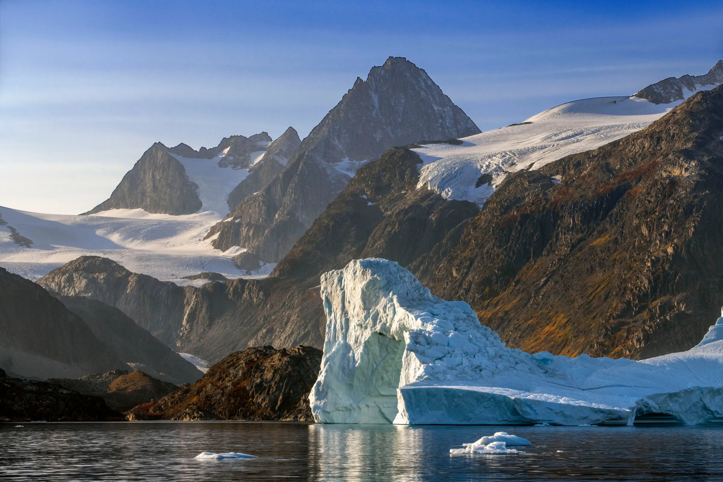 Skjoldungen Fjord, a large iceberg  surrounded by snow-capped mountains, Southeast coast, Greenland. 