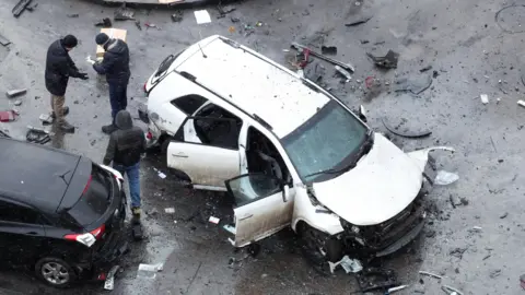 Reuters Investigators work near a damaged car