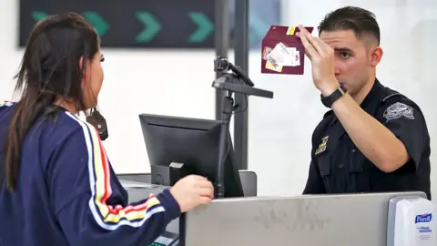 Getty Images A US CBP officer checks the passport of a traveller