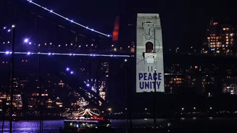 AFP via Getty Images A message reading "Peace, Unity" is projected on the pylon of the Sydney Harbour Bridge
