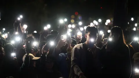 EPA A group of spectators shining lights from their mobile phones during a tribute to the victims of the Bondi terror attack during the New Year's Eve Celebrations at Mrs Macquaries Point in Sydney, Australia