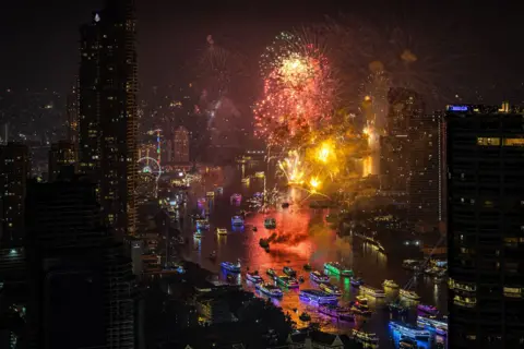 Getty Images Fireworks over the Chao Phraya river in Bangkok, Thailand, lighting up the skyline and boats