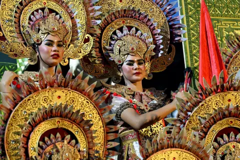 AFP via Getty Images Balinese woman pose before they perform a traditional to release the sun of 2025, and to welcome the sun of 2026, during a New Year's Eve celebration in Denpasar, on Indonesia's resort island of Bali on December 31, 2025.