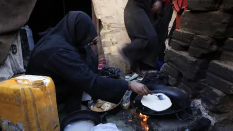 EPA A displaced Yemeni woman prepares food for her family at a makeshift camp in Sanaa, Yemen (24 December 2025)