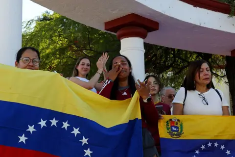 AFP via Getty Images group of women crying and smiling as they hold up Venezuela flags