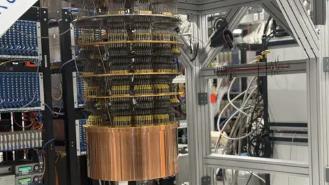Google's Willow quantum computer is an oil barrel-sized series of round discs connected by hundreds of black control wires descending into a bronze drum suspended a metre from the ground in a lab