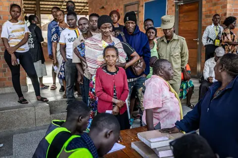 AFP via Getty Images Voters queue to cast their ballots at a polling station in Kampala 
