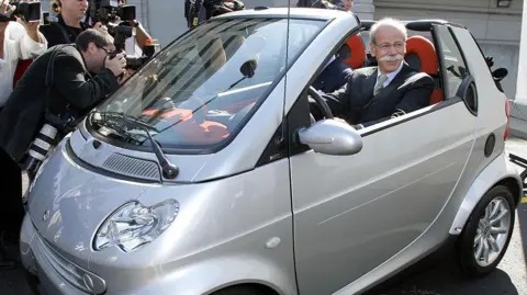 Getty Images DaimlerChrysler AG Chairman Dieter Zetsche poses for photographers while sitting in the two-seat Smart car after a press conference to introduce the car to the media in June, 2006