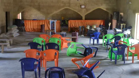 Reuters The inside of Haske Cherubim and Seraphim Movement Church, after an attack by gunmen in which worshippers were kidnapped.  There are orange, green and blue plastic chairs scattered on the floor. 