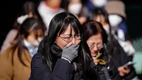 Xinhua A woman places her hand against her face as she sobs