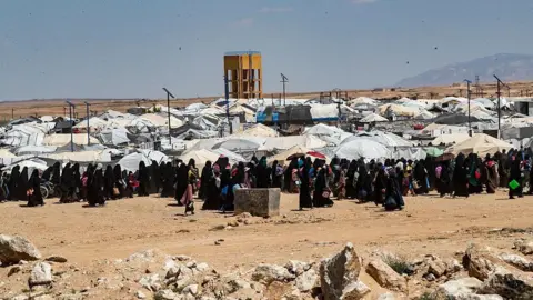 AFP File photo showing people walking around al-Hol camp, in Hassakeh province, north-eastern Syria (18 April 2025)