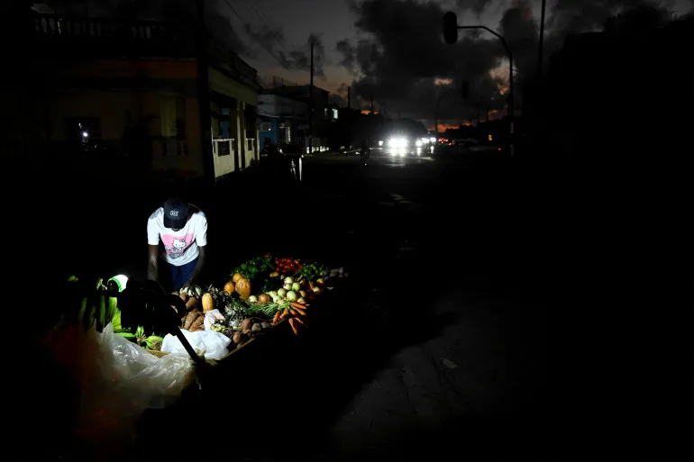 A man sells vegetables on the street during a blackout in Havan