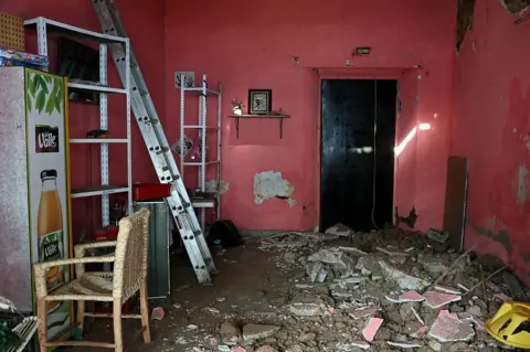 Getty An image showing damage inside a pink house after a 6.5 magnitude earthquake in the community of San Marcos, Guerrero state, Mexico. The floor is covered in a pile broken concrete, rubble, and dirt, while a ladder is positioned on the left near shelves and a chair.