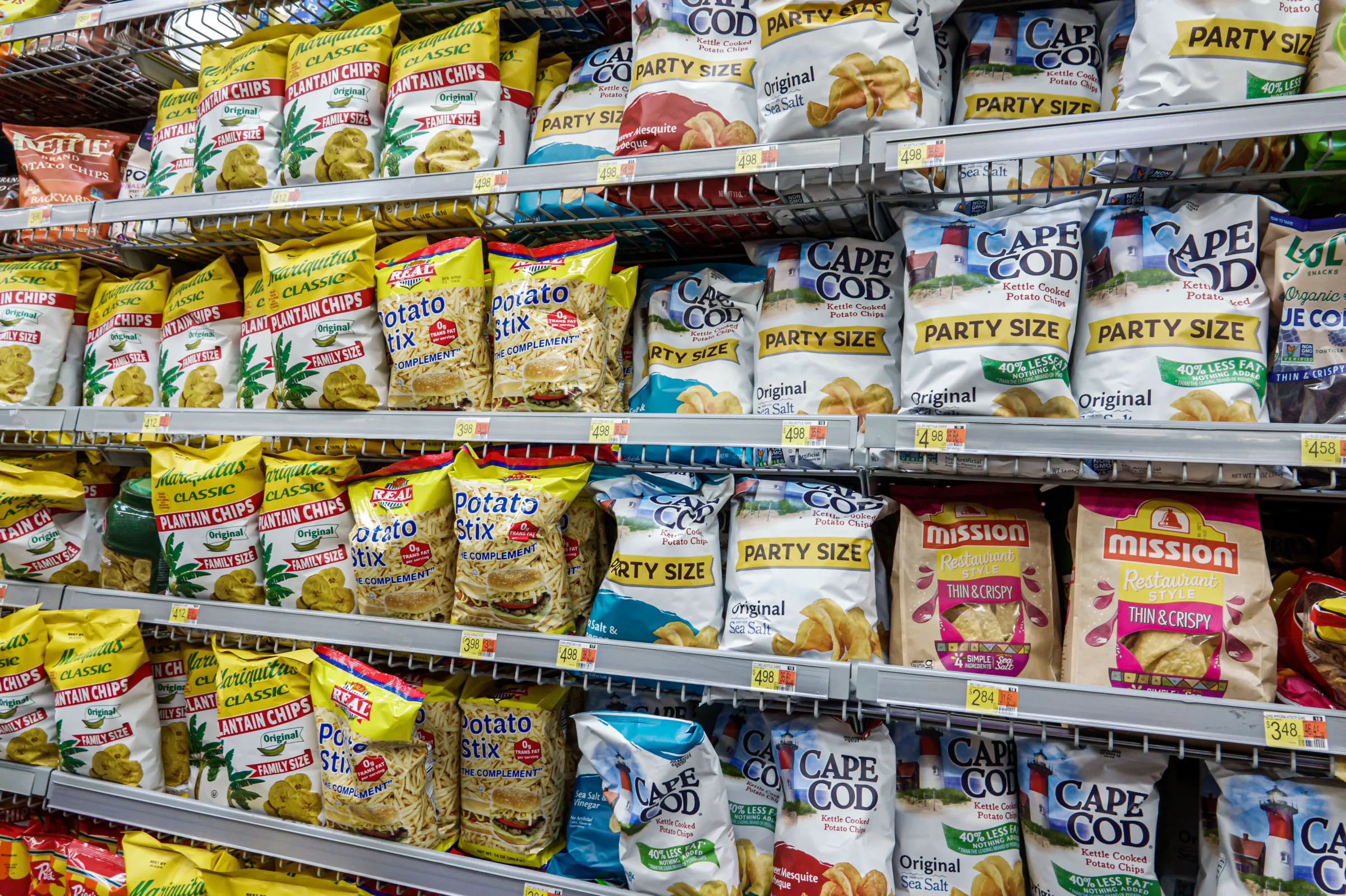An aisle full of potato chips and snacks in rows on grocery store shelves.