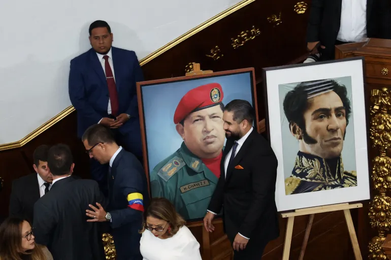 Nicolas Maduro Guerra walks past a portrait of his father