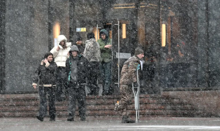 A wounded Ukrainian serviceman walks in a street in Kyiv during snow fall on February 15, 2026, amid Russian invasion in Ukraine. (Photo by Sergei SUPINSKY / AFP)