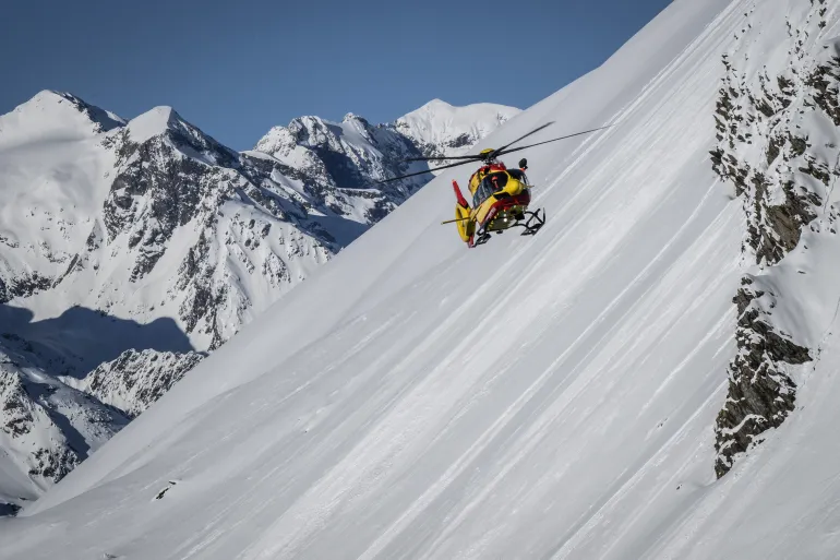 A Securite Civile helicopter (emergency management) flies over an off piste area around the Alpe d'Huez, French Alps