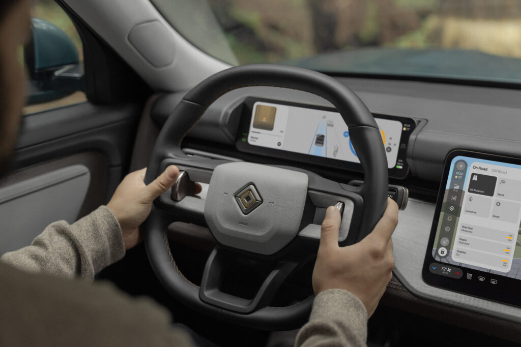 Hands hold a Rivian R2 steering wheel.