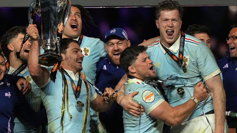 Antoine Dupont of France, holds the trophy aloft after clinching the title