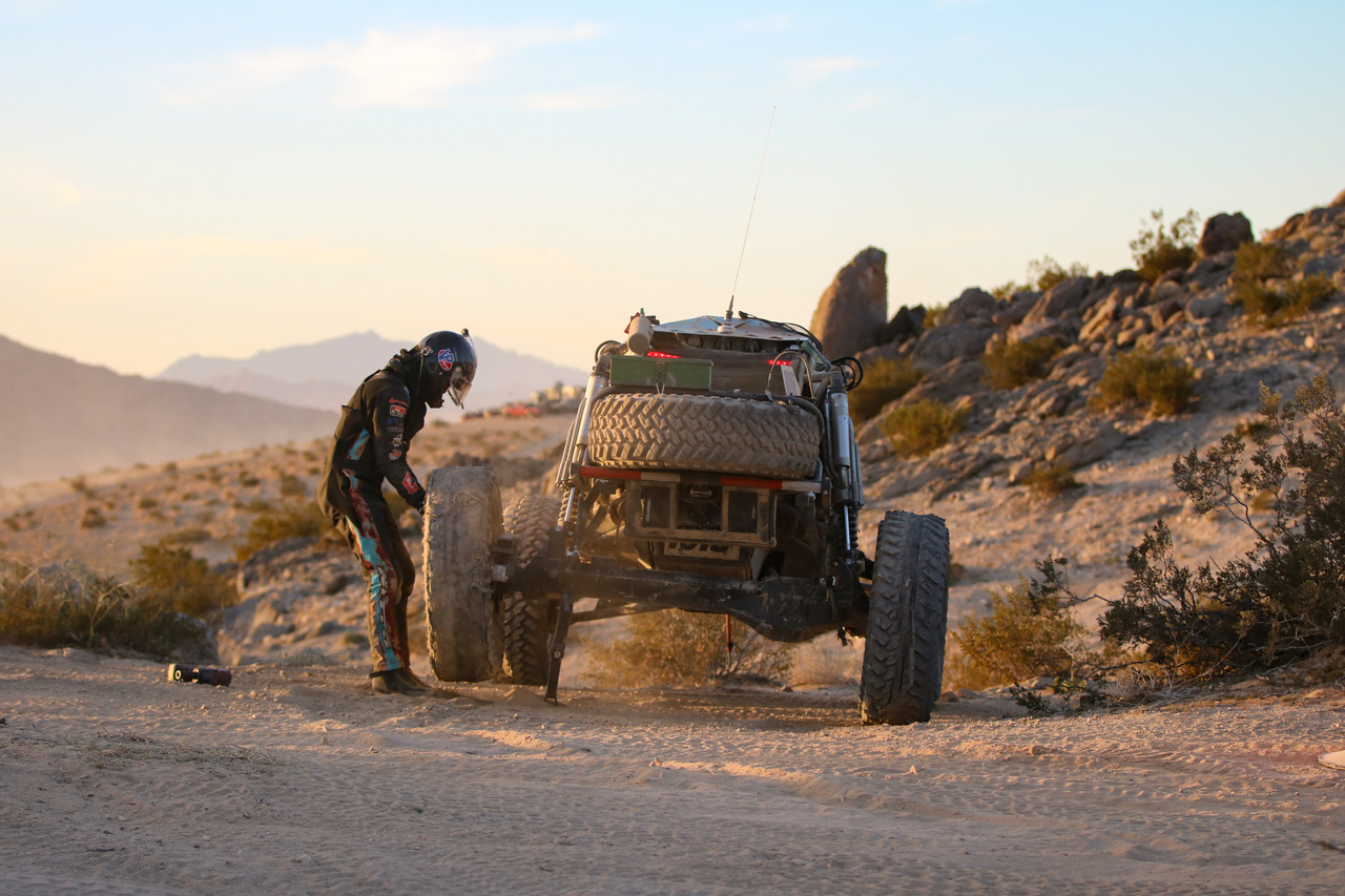 A man fixes a wheel on his off-road racing car