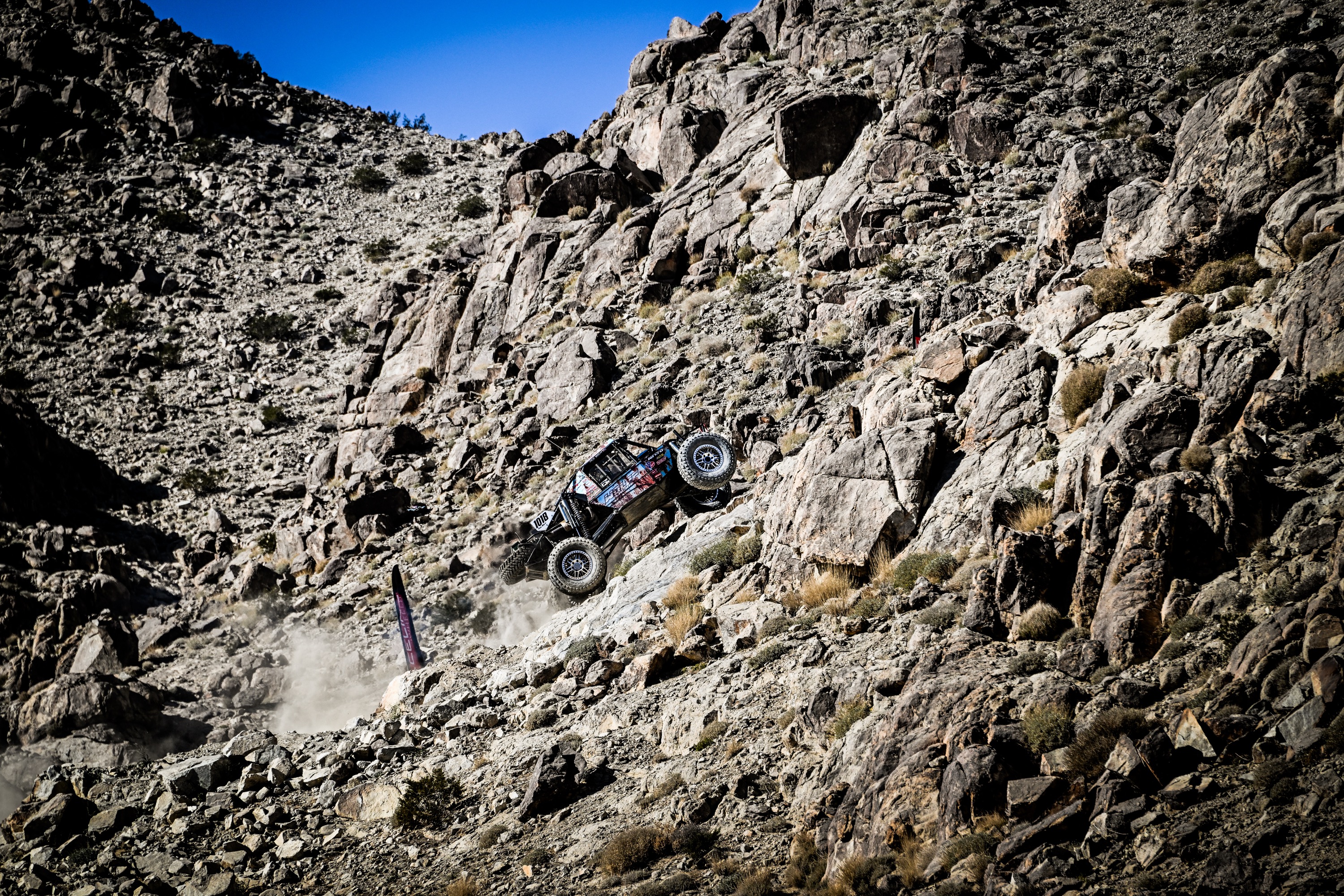 An off-road race car drives up a 45-degree slope