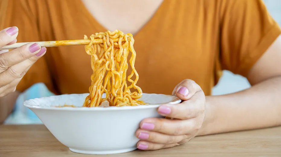 a woman picks up instant noodles with chopsticks