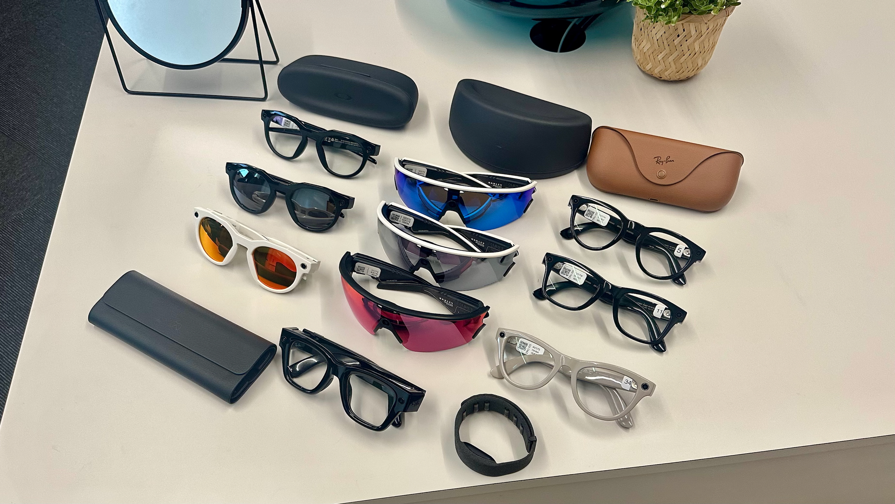 Oakley Meta HSTN, Meta Vanguard, and Ray-Ban Meta (Gen 2), each in various styles, are sitting atop a table, with the Meta Ray-Ban Display glasses in front of them.