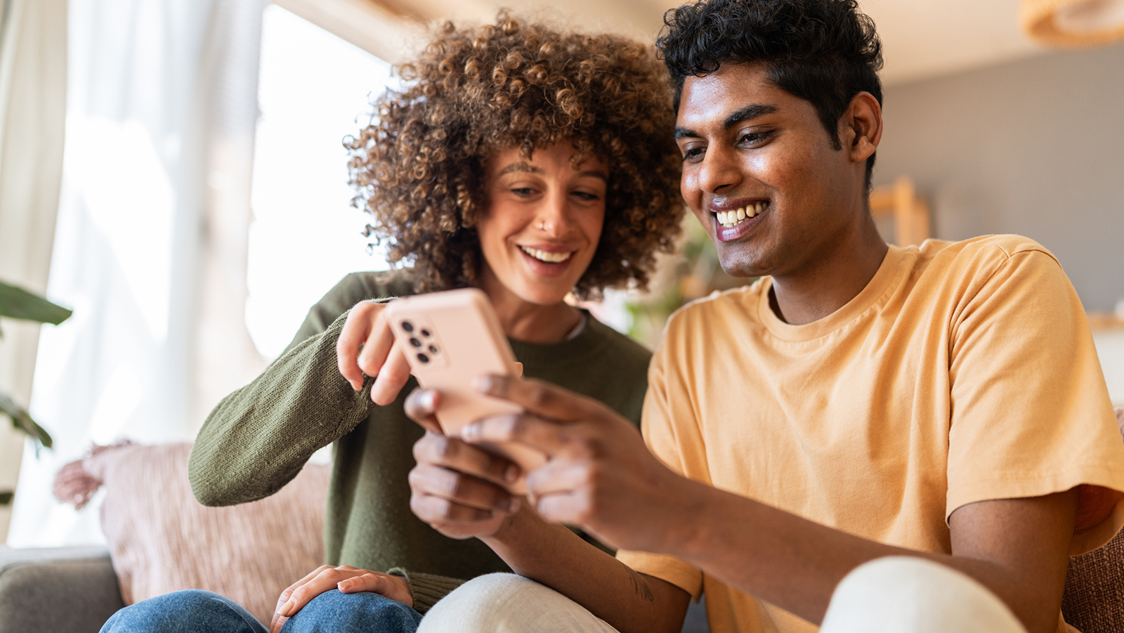 Two people looking at a smartphone together on a sofa