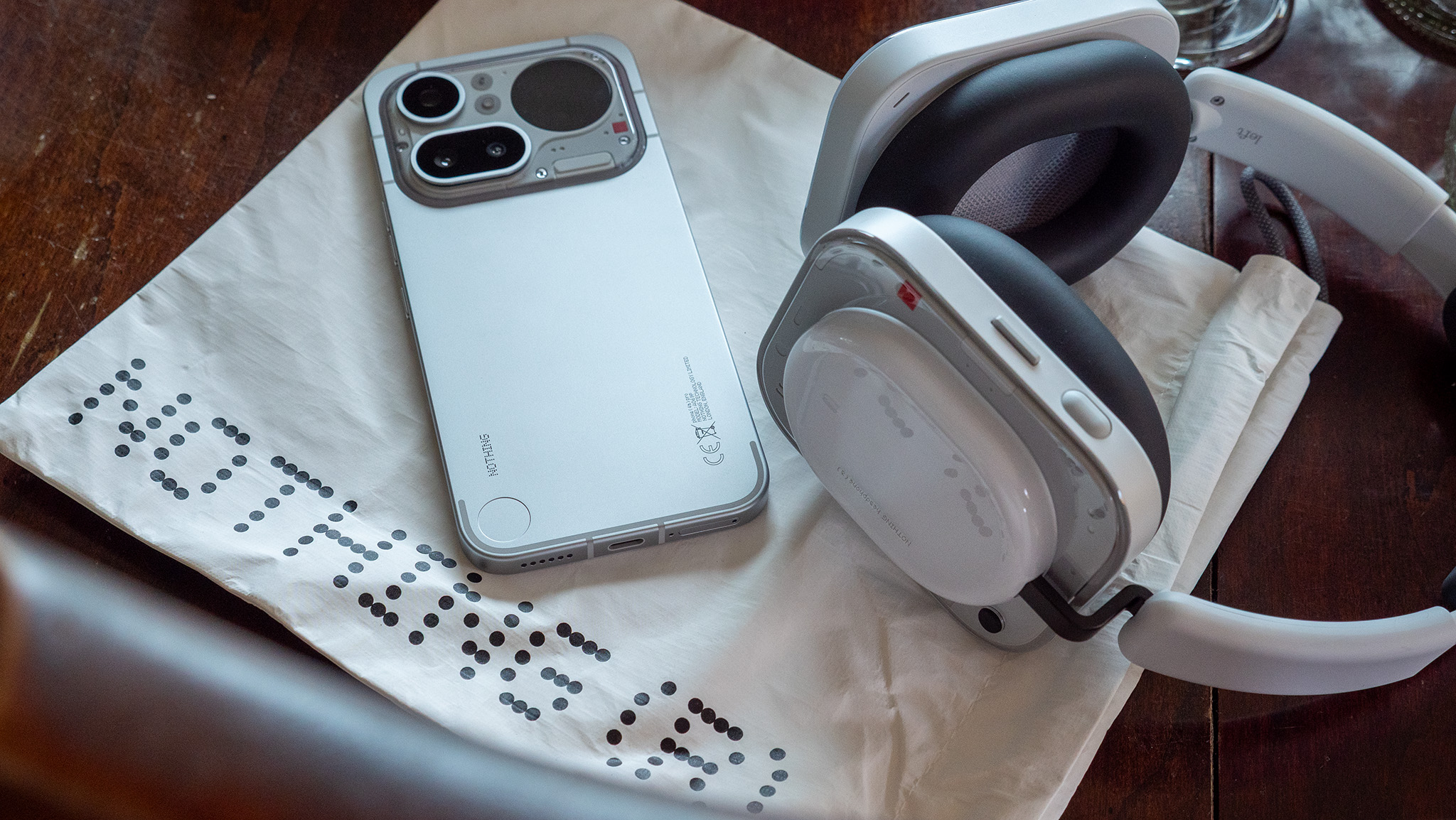 A Nothing Phone 4a Pro and a Nothing Headphone A on a Nothing-branded bag