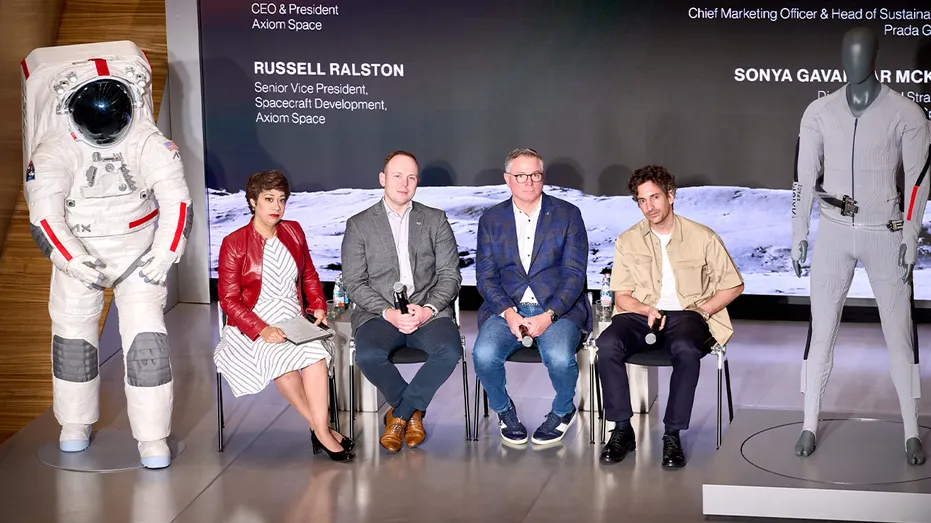 panel discussion with four members and spacesuit models to the side