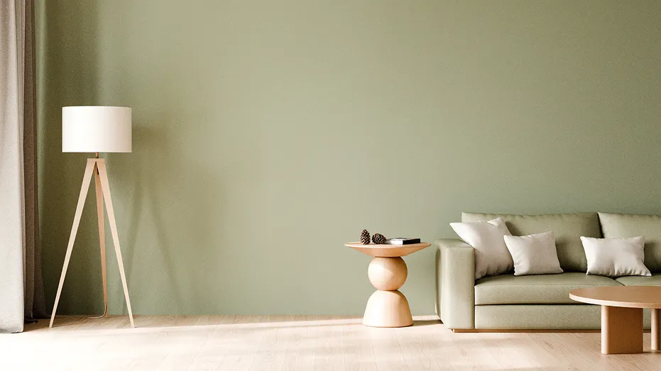 A sage green living room features a matching sofa, wooden accent tables and a tripod floor lamp. Zillow said sage green was one of the safest paint choices for sellers.