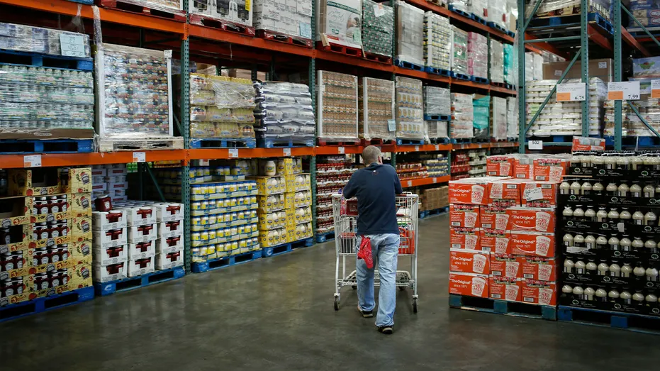 Shopper pushing cart through aisle at Costco.