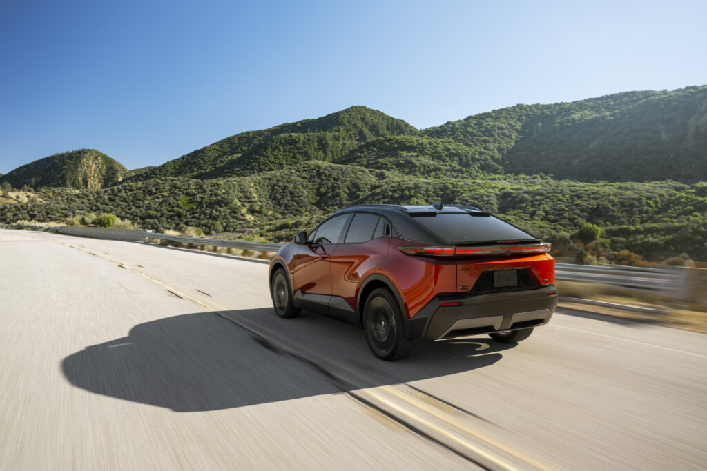 A red Toyota C-HR drives away from the camera