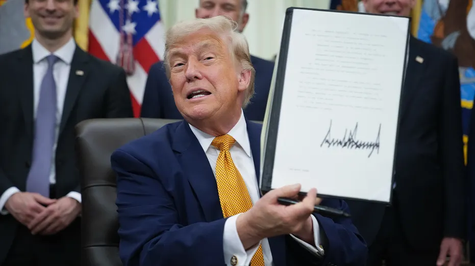 U.S. President Donald Trump shows an executive order he signed in the Oval Office of the White House