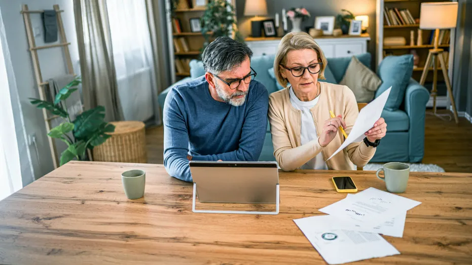 A couple prepares their taxes at a kitchen table.