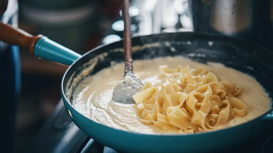 Fettuccine Alfredo being prepared in a pan