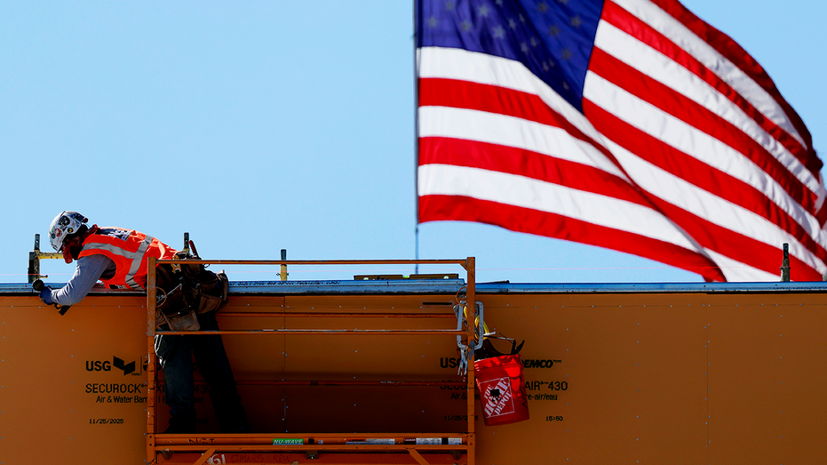 American flag flies near a construction worker.
