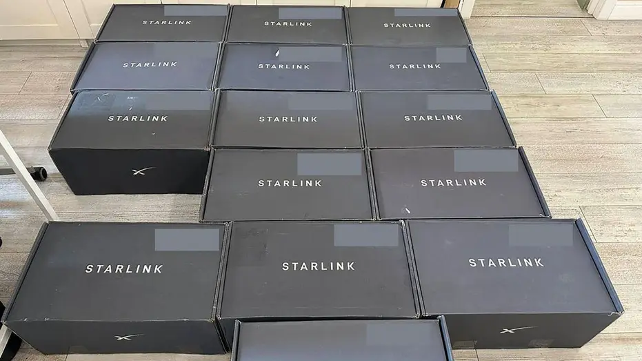 Multiple black Starlink boxes laid out in rows on a floor, each box marked