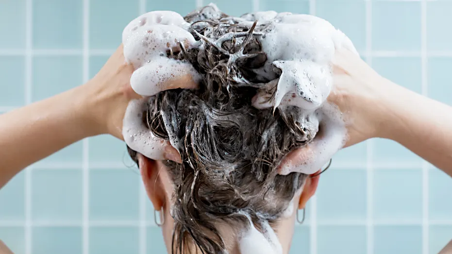 A woman shampoos her hair.