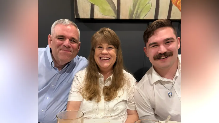 Roger Owens, Aimee Owens and their son, Alex Owens, smiling together while seated at a restaurant table.