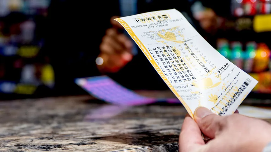 A lottery ticket is held over a counter.