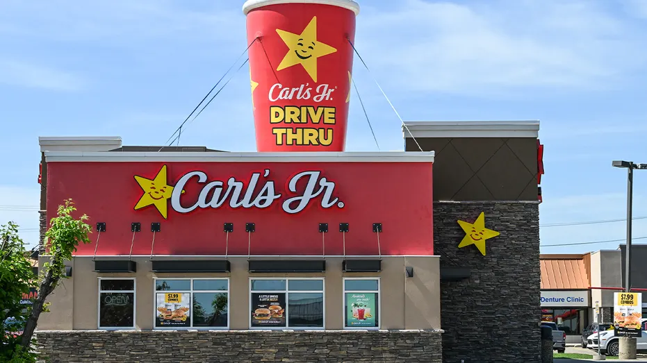 a big carl's jr logo shaped like a drink is propped on top of a fast food location